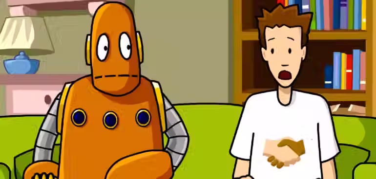 Tim and Moby sit on a couch. Tim's shirt has a handshake on it. 