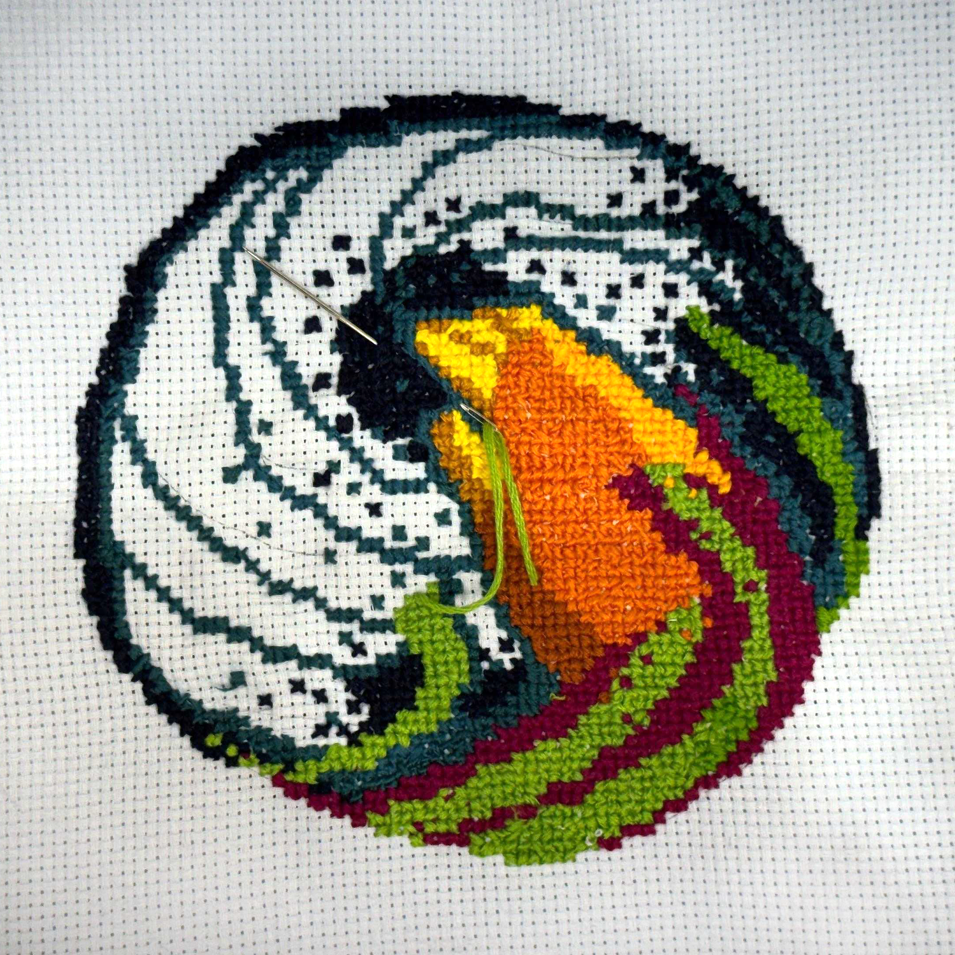 Cross-stitch artwork depicting Moby's hand holding up a colorful dot, stitched in a swirling design of black, white, and rainbow thread.