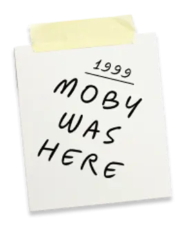 Note taped to a surface, reading "1999 Moby Was Here" in bold, black handwritten text. A playful, nostalgic mood is conveyed.