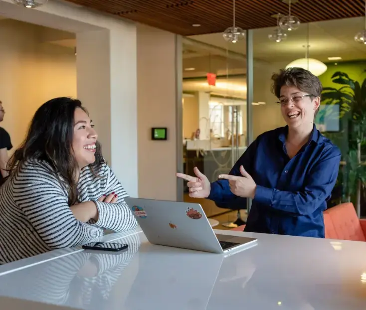 Two BrainPOP employees laughing with finger guns in the BrainPOP office